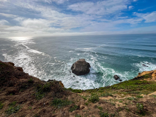 View over a tall cliff overlooking rocky outcrops in the ocean