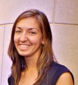 White woman in front of a stone building.