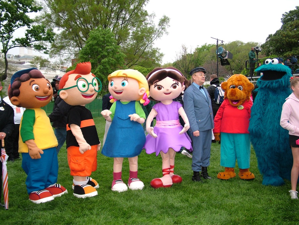 Several Strolling Characters stand on the White House lawn. 