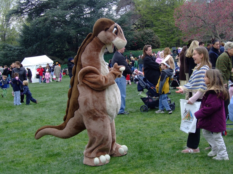 A strolling character greets two children. 