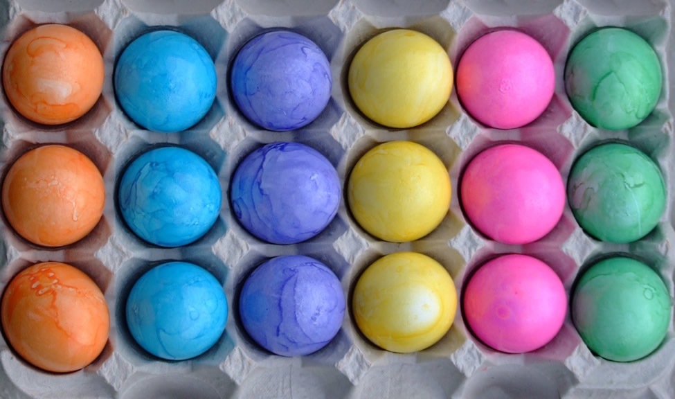 Dyed eggs sit in a milk carton
