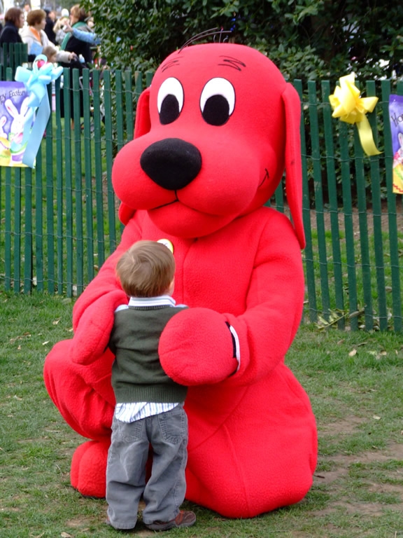 Clifford the Big Red Dog hugs a young child. 