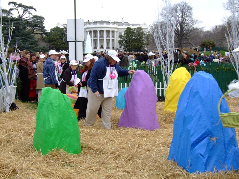 Volunteers hide eggs in hay for the next group of children.