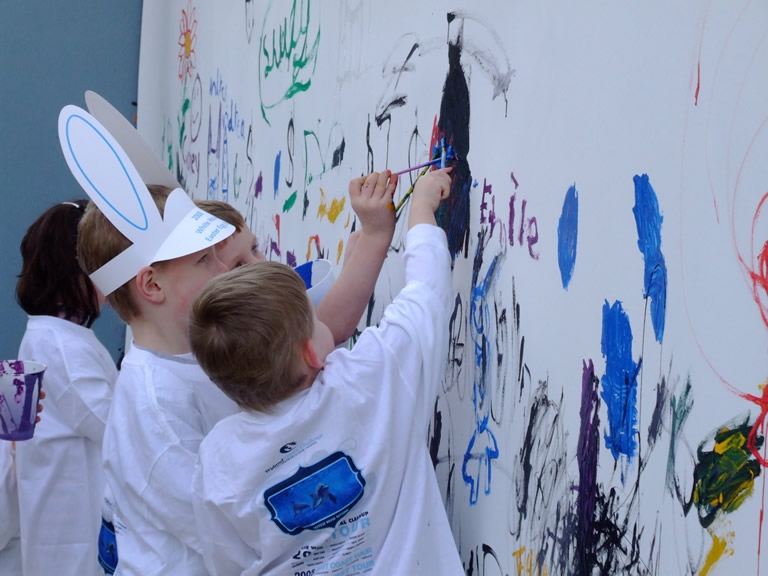 Children paint a large white canvas on the South Lawn of the White House.