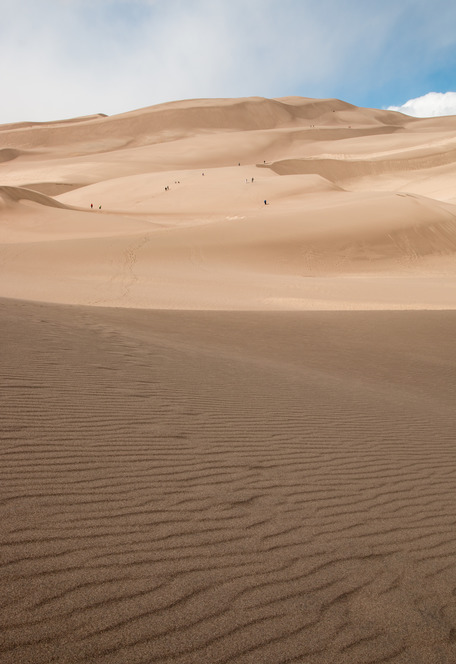 Visitors walk up the large dunes at the beginning of the dune field.