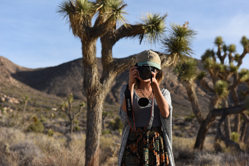 a young woman looks through a camera