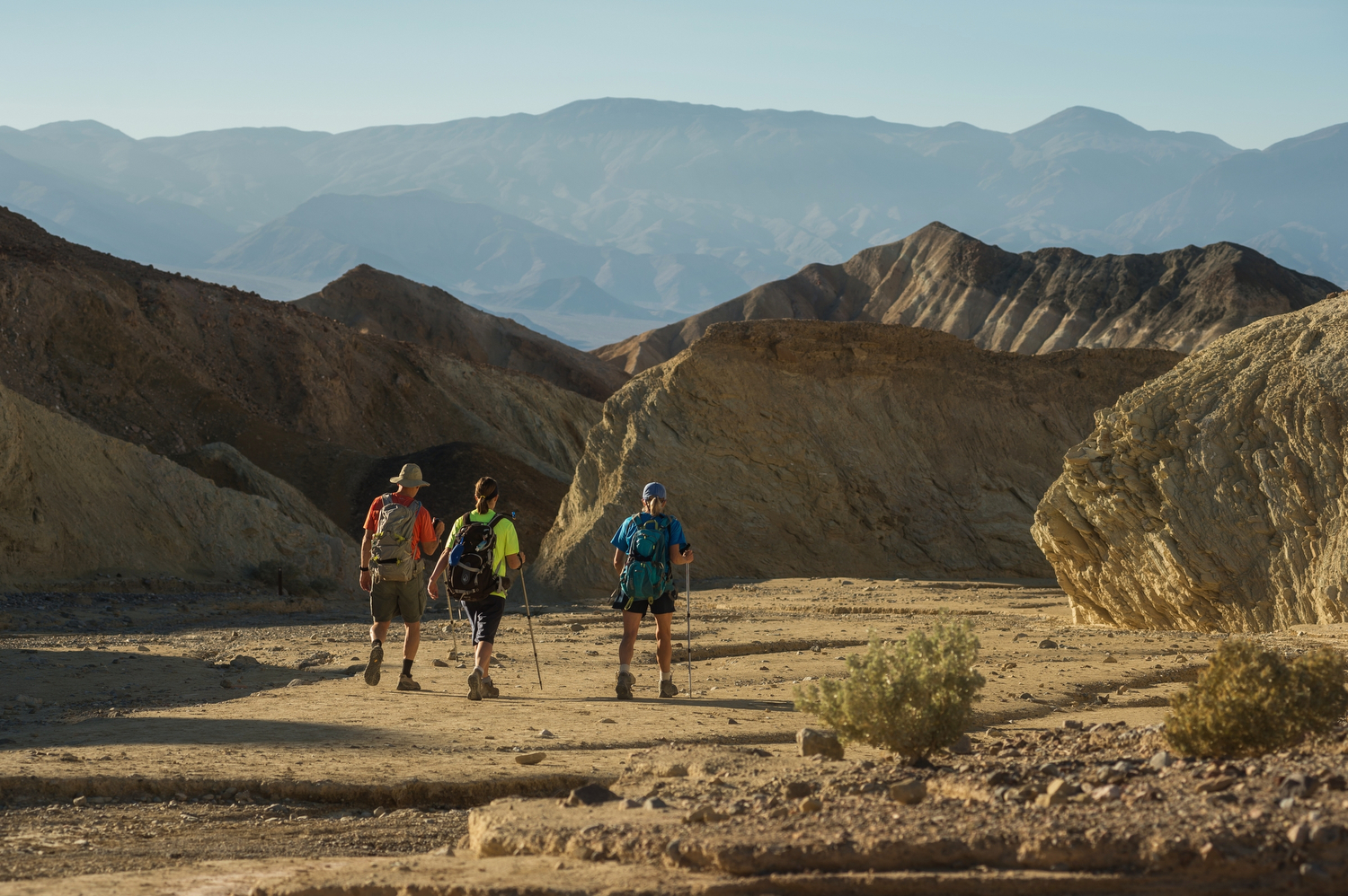 Three hikers walk away from the camera in Death Valley National Park.