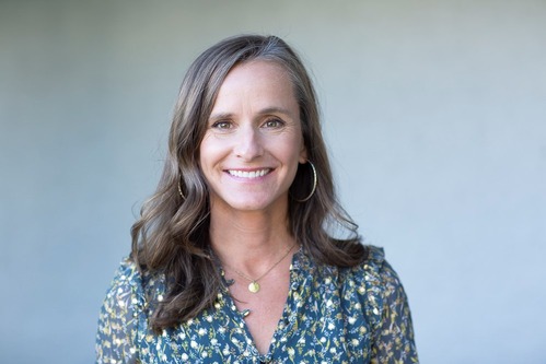 White woman in front of a white background.