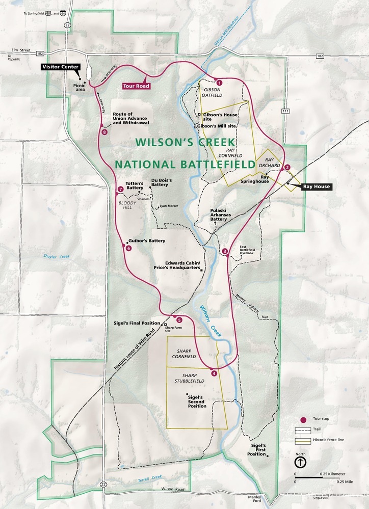 Map of Wilson’s Creek National Battlefield in Missouri. Spanning the map from north to south, the roughly rectangular site is shown in sage green with pockets of beige and a dark magenta Tour Road with 8 numbered stops. The surrounding terrain is pale green and ivory white.