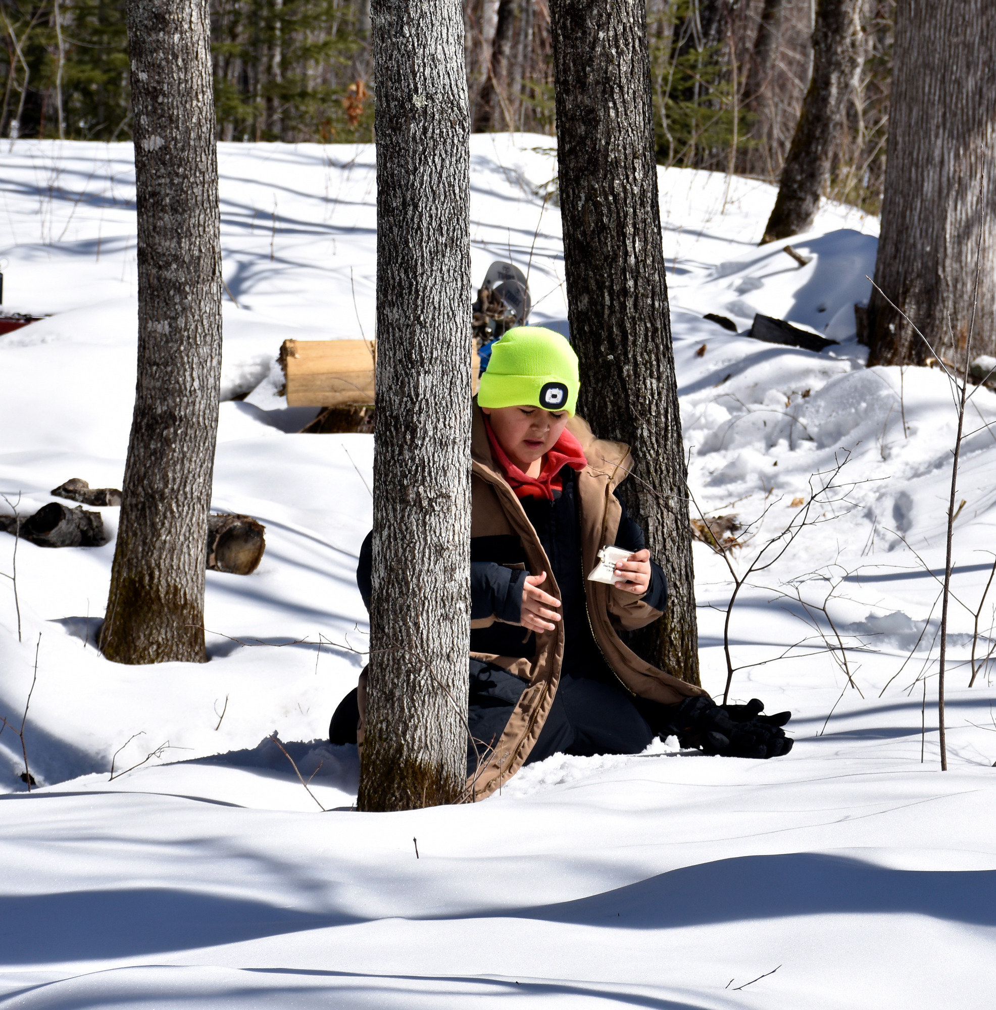 A child kneels on the snow with an open hand.