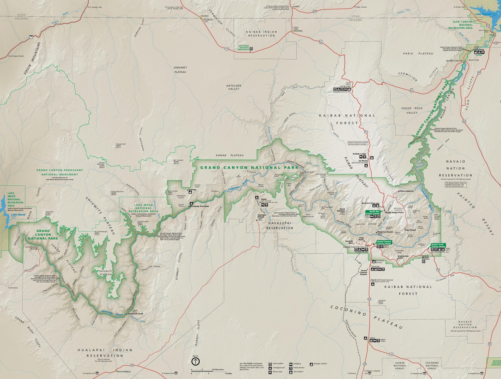 Map of Grand Canyon National Park in Arizona. Outlined in green, the park follows the shallow, sideways S-curve of the Colorado River across the middle of tan-colored terrain. Dozens of peaks, plateaus, points, overlooks, cliffs, gorges, bodies of water, reservations, valleys, and other sites are labeled across and around the park.