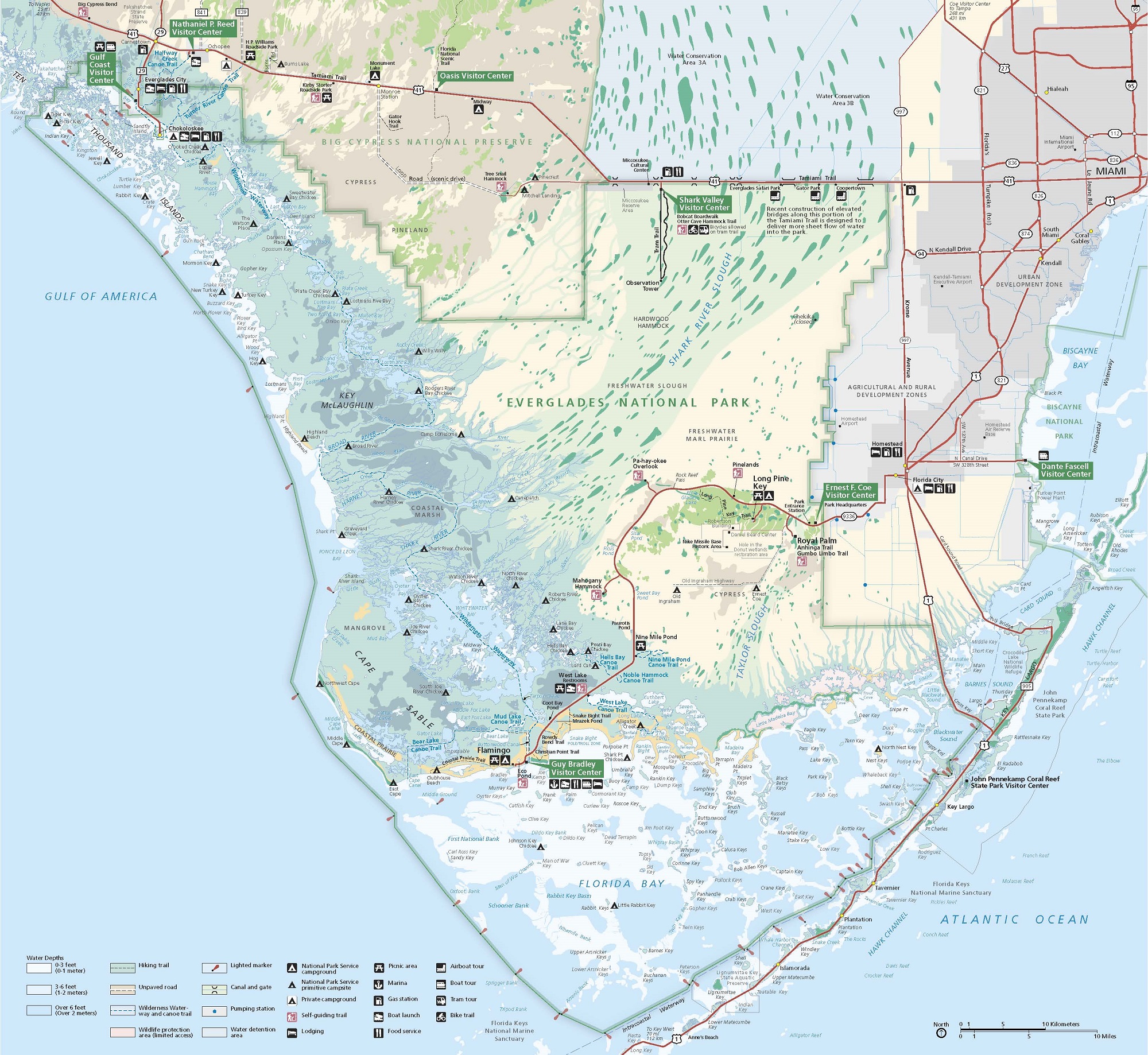 Map of Everglades National Park in Florida. Everglades encompasses the southern tip of Florida south of the Big Cypress National Preserve in the northwest, Miami to the northeast, and Biscayne National Park to the southwest. The map includes an array of colors including pale green, light brown, pale yellow, light blue, dark blue, light gray, and dark gray.