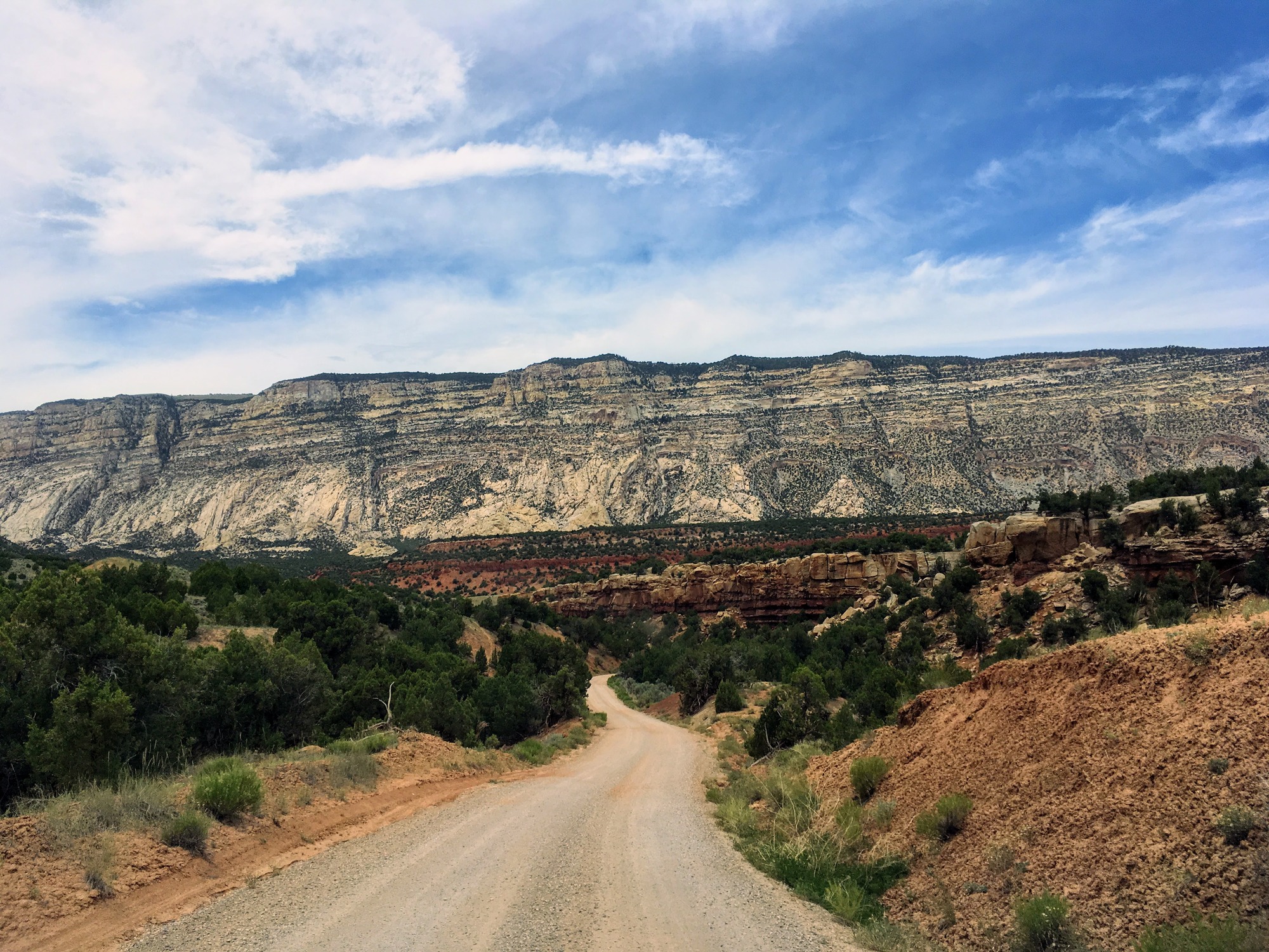 Echo Park Road winds away towards geologic features of many colors towering in the distance. 