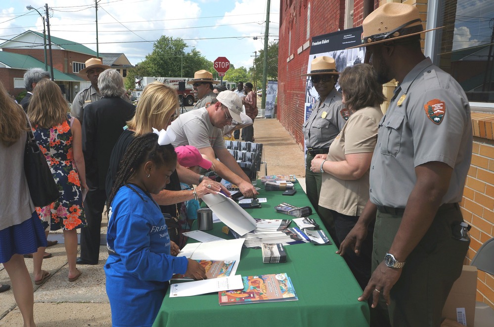 park rangers staffing information table with public young and old receiving information and brochures