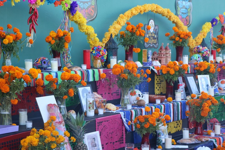 Colorful three-tiered altar with marigolds, photos, and candles. 