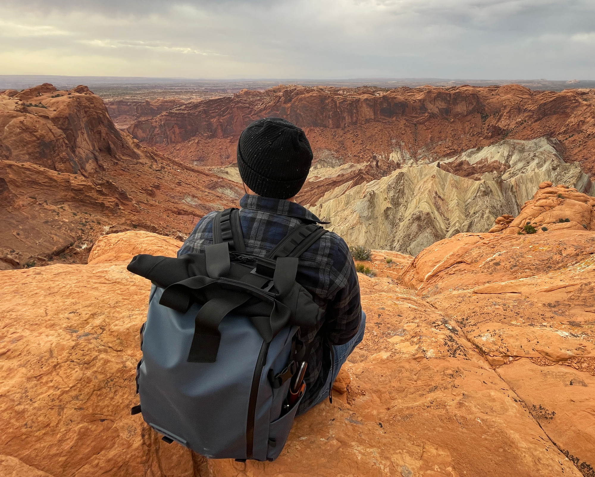 Person sitting down on a rock while looking at a a circular structure made out of different rock layers. 