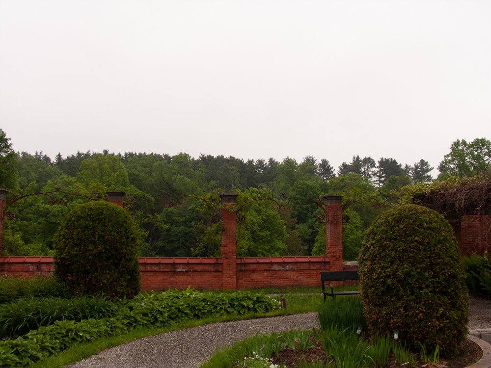 A gravel garden path leading toward a brick trellis.