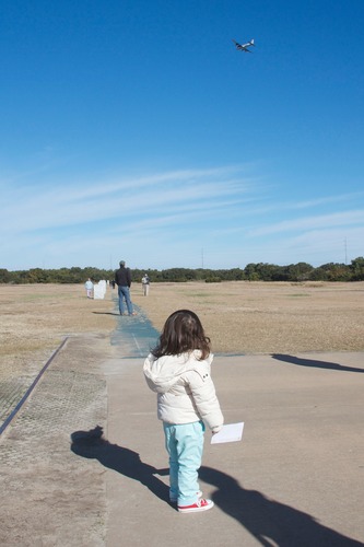 A young girl watches a plane fly overhead