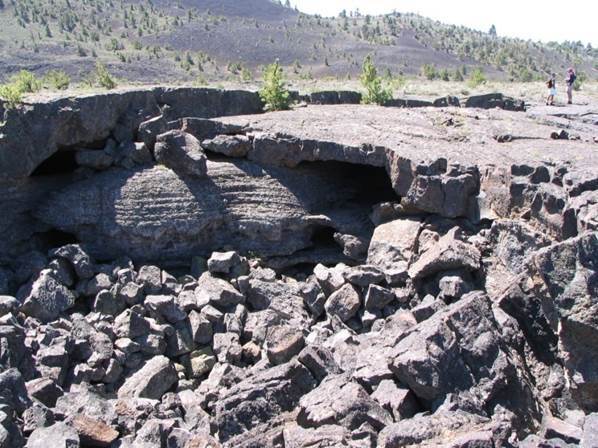a lava tube cave that has collapsed and filled with broken rocks, revealing part of a passage stretching left and right