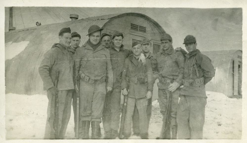 Group of men posing in front of a quonset hut