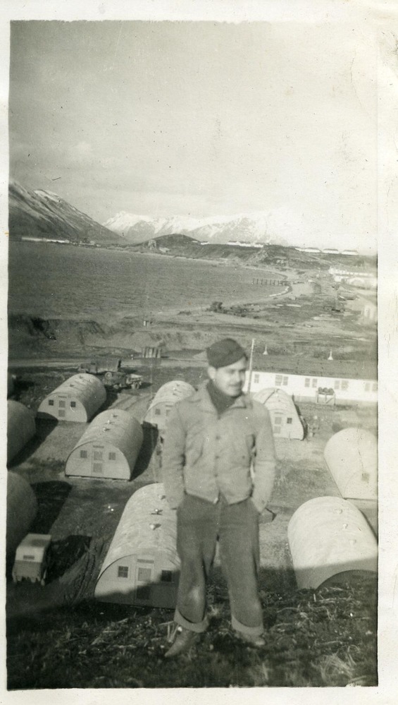 Man on hill in front of quonset huts