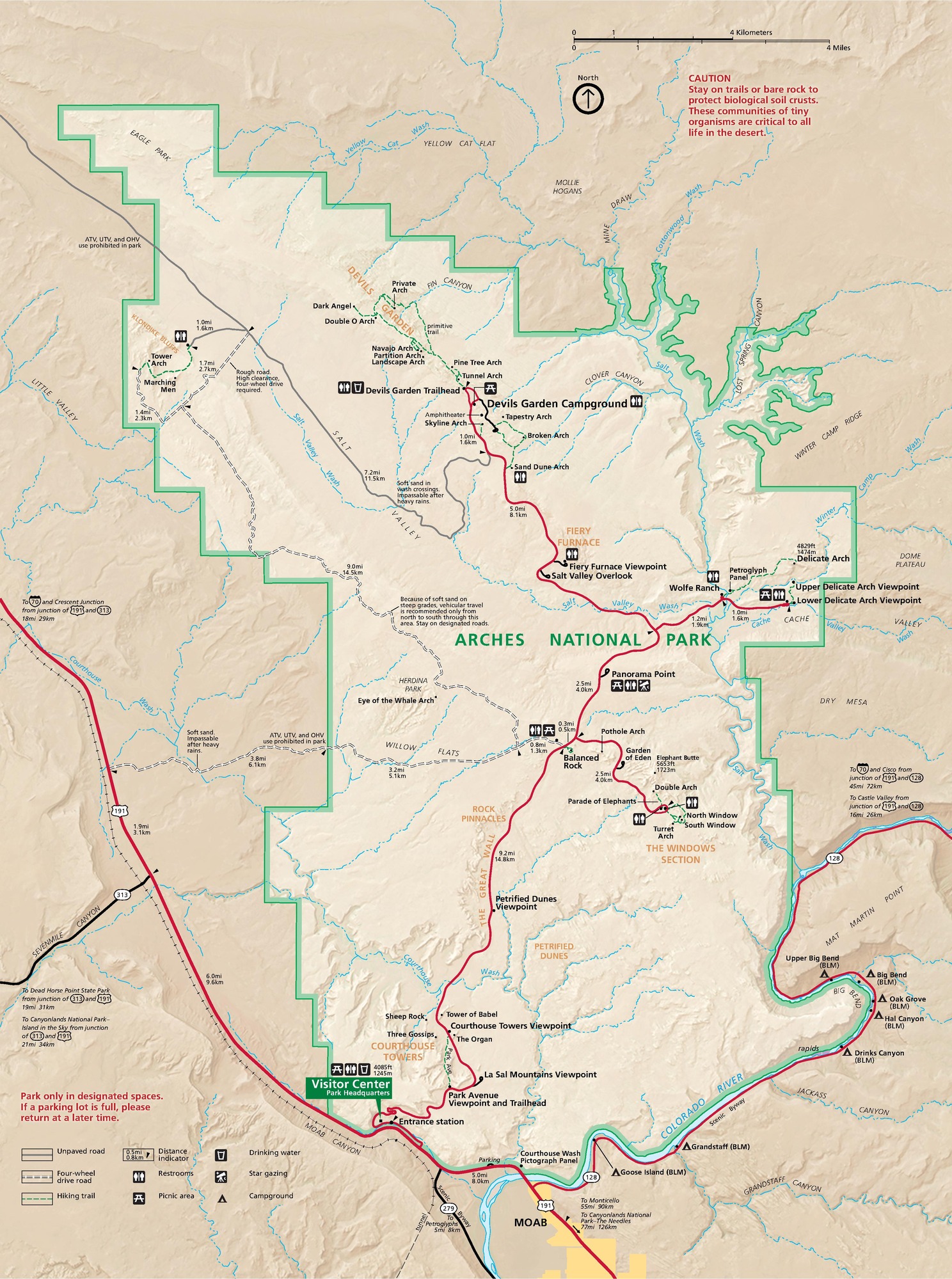 Map of Arches National Park in Utah. The park is roughly rectangular, but irregularly (?) shaped with deeply stepped sides. The borders are shaded in green, and the area inside is beige. Surrounding terrain is a darker tan. Rivers are shown as blue lines and major roads as red lines.