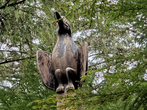 A carving of a large black bird sitting on top of a totem pole.