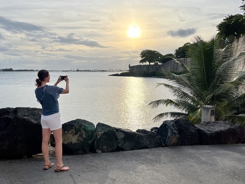 A person taking a photo of a historic city stone wall around a bay