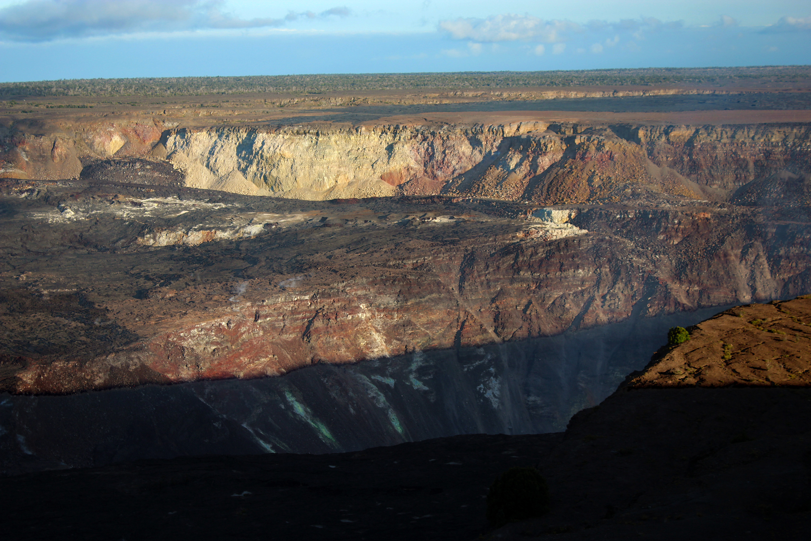 A volcanic crater landscape with yellow, brown and white sulfur and mineral deposits 