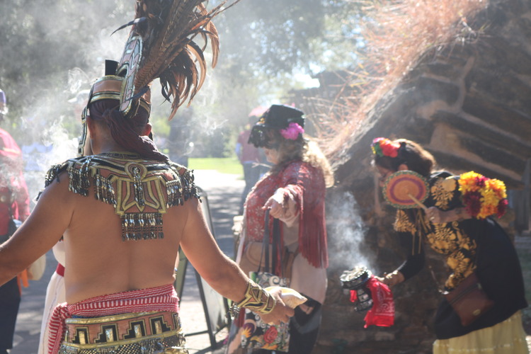 Man with Aztec inspired dress surrounded by smoke. 