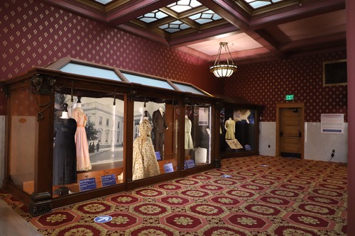 A large display case filled with five dresses. 