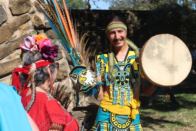 Male dancer with colorful Aztec inspired outfit holding a hand-held drum. 