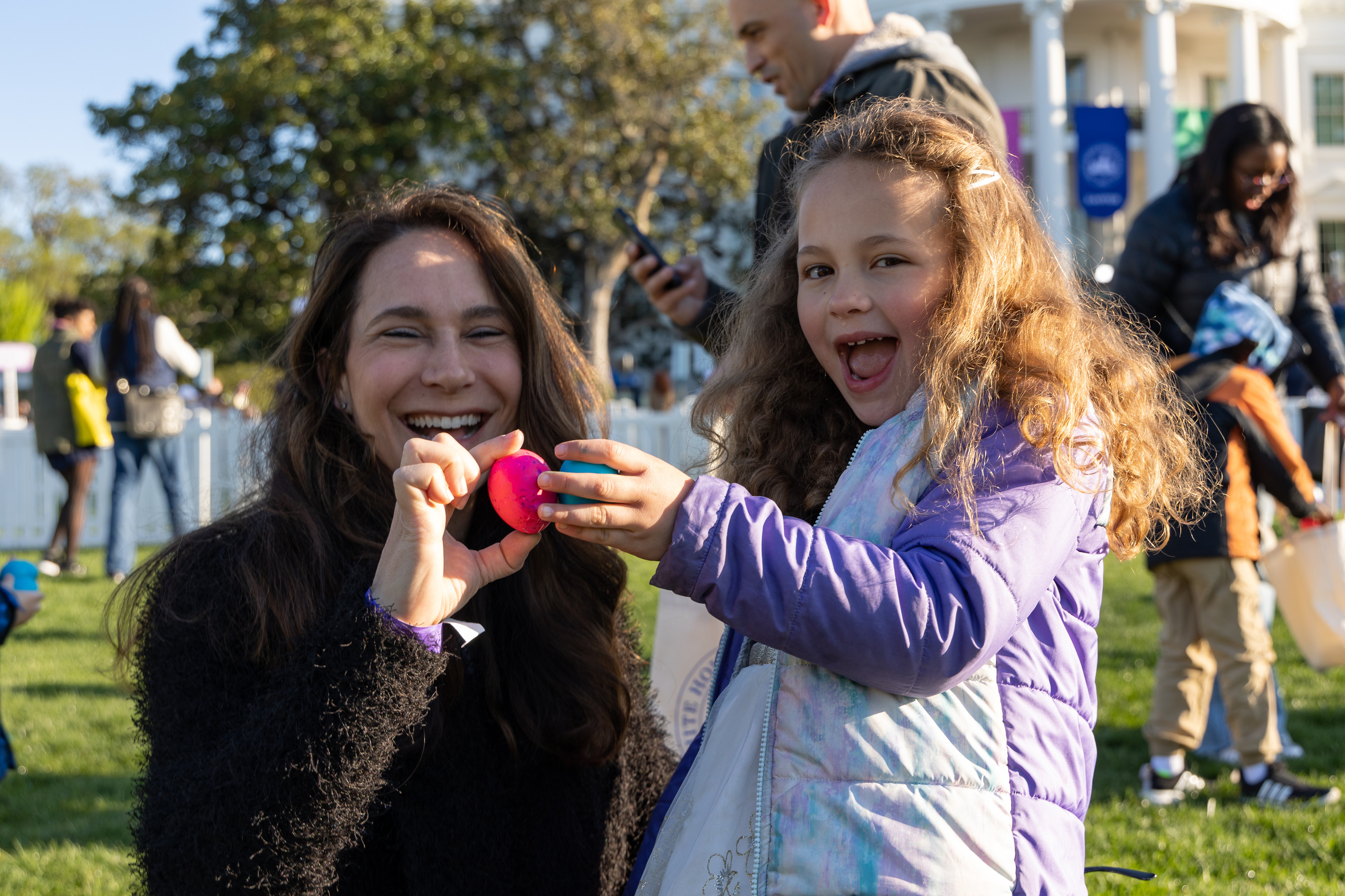 A mother and her daughter pose with easter eggs in front of the white house