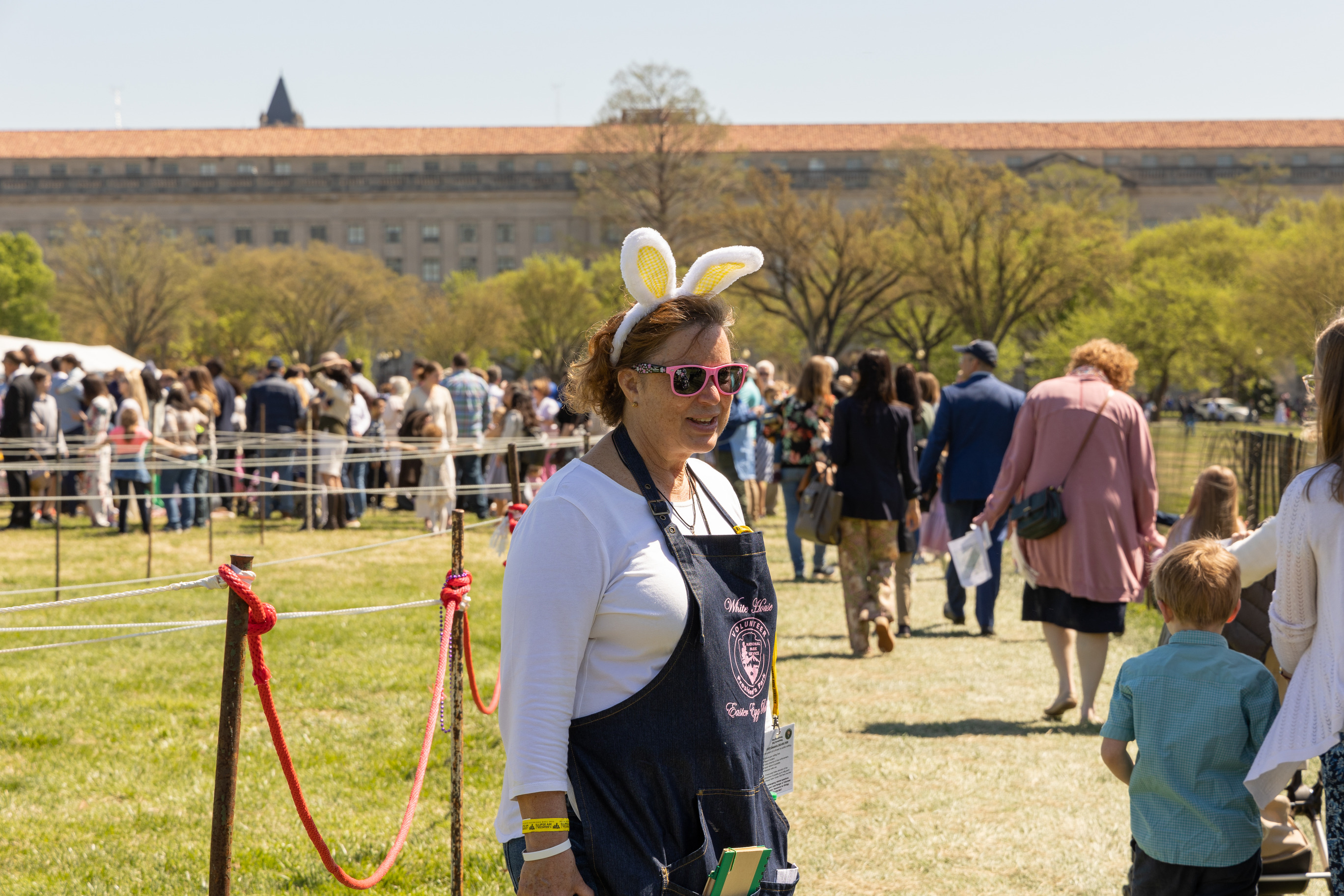 A volunteer with bunny ears helps a crowd 