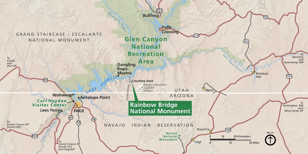 Area map of Rainbow Bridge National Monument in Utah. A straight white horizontal line separates Utah above to Arizona across the bottom third of the map. The monument is labeled with a green callout box. Other parks are shaded green or tan.