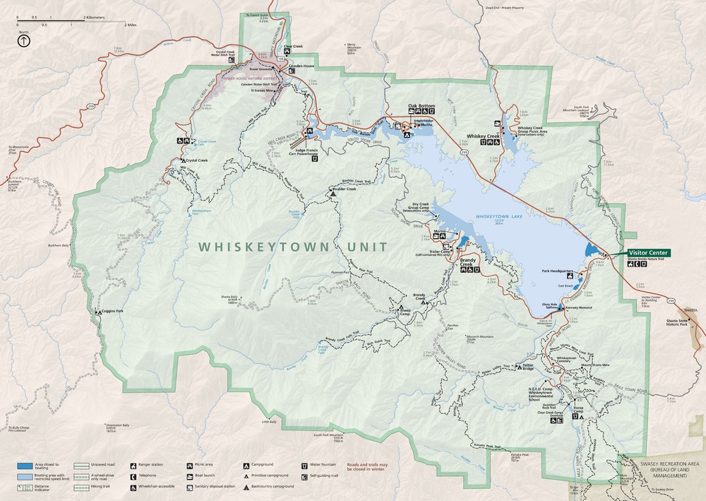 Map of Whiskeytown National Recreation Area in California. Whiskeytown Unit is roughly rectangular with curved edges along the west and south borders and stepped sides along north and east. The park is shaded green and the surrounding territory is beige. Whiskeytown Lake, shaded in blue, fills up much of the park's northeastern corner.