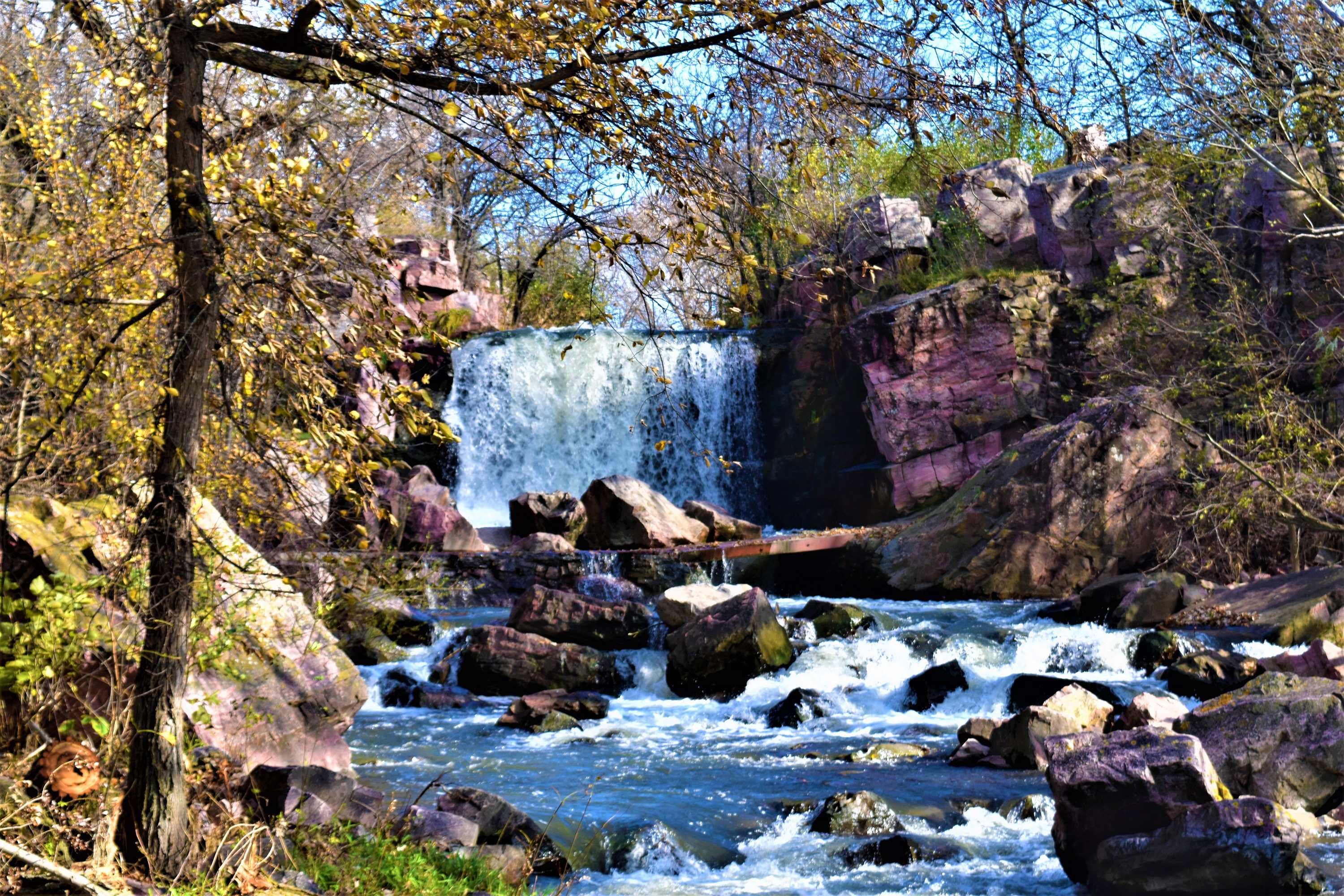 Waterfall surrounded by pink rock and trees turning color