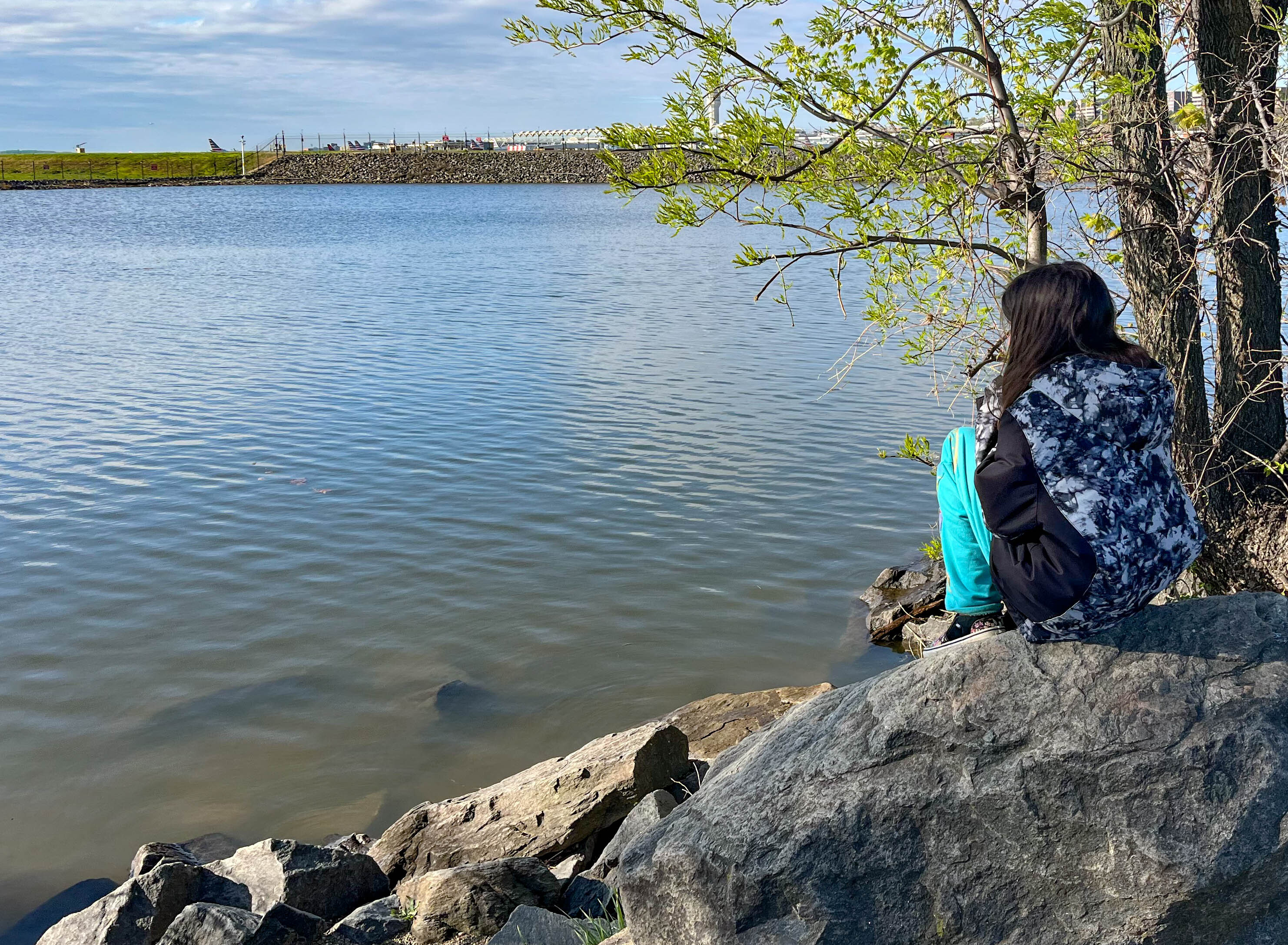 Kid sitting on a rock looking at the river