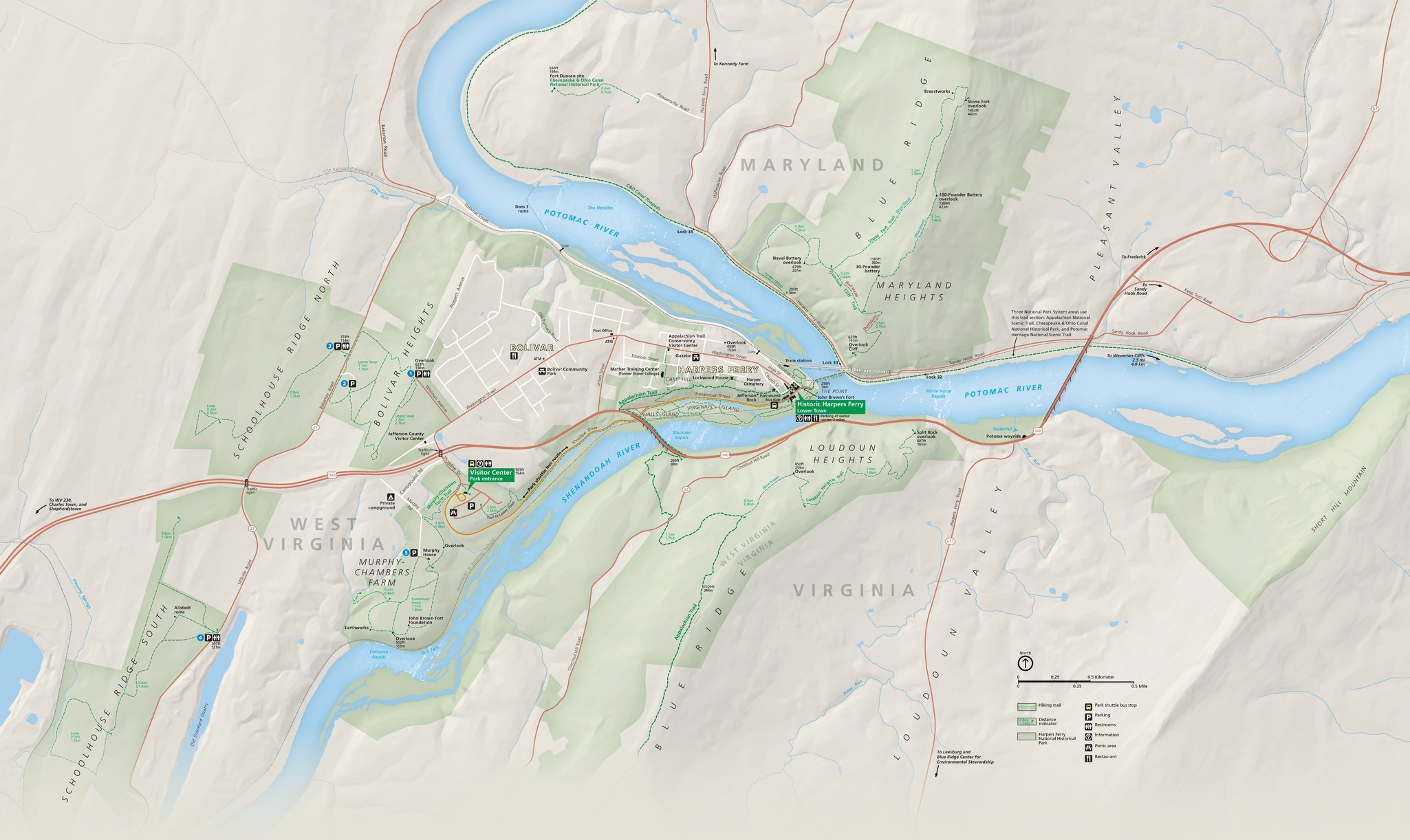 Map of Harpers Ferry National Historical Park where Maryland, Virginia, and West Virginia meet. The park is highlighted in green with the surrounding area in tan. A sideways-oriented Y-shaped river cuts through the park. Major highways are represented by orange lines, the street grid by white lines, and trails by dashed green lines.