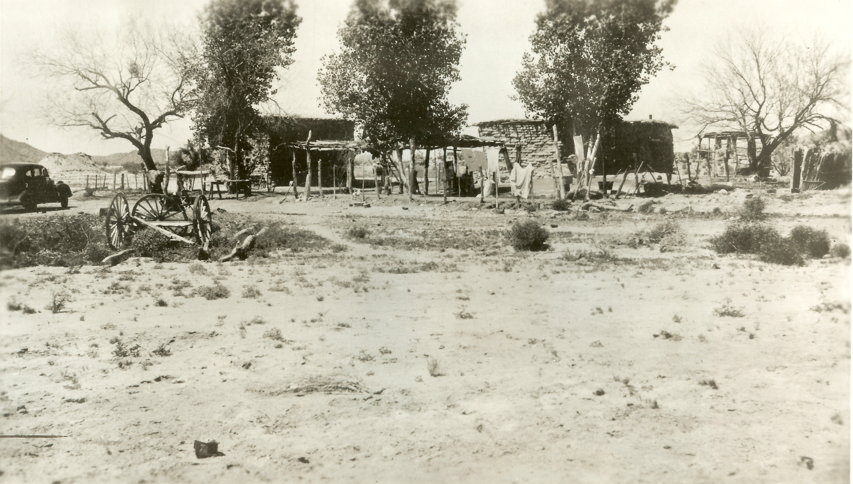 The Orozco family's adobe homes, ramadas, and shade trees near the banks of Quitobaquito Springs. A small buggy car and wagon are visible in the middle left.