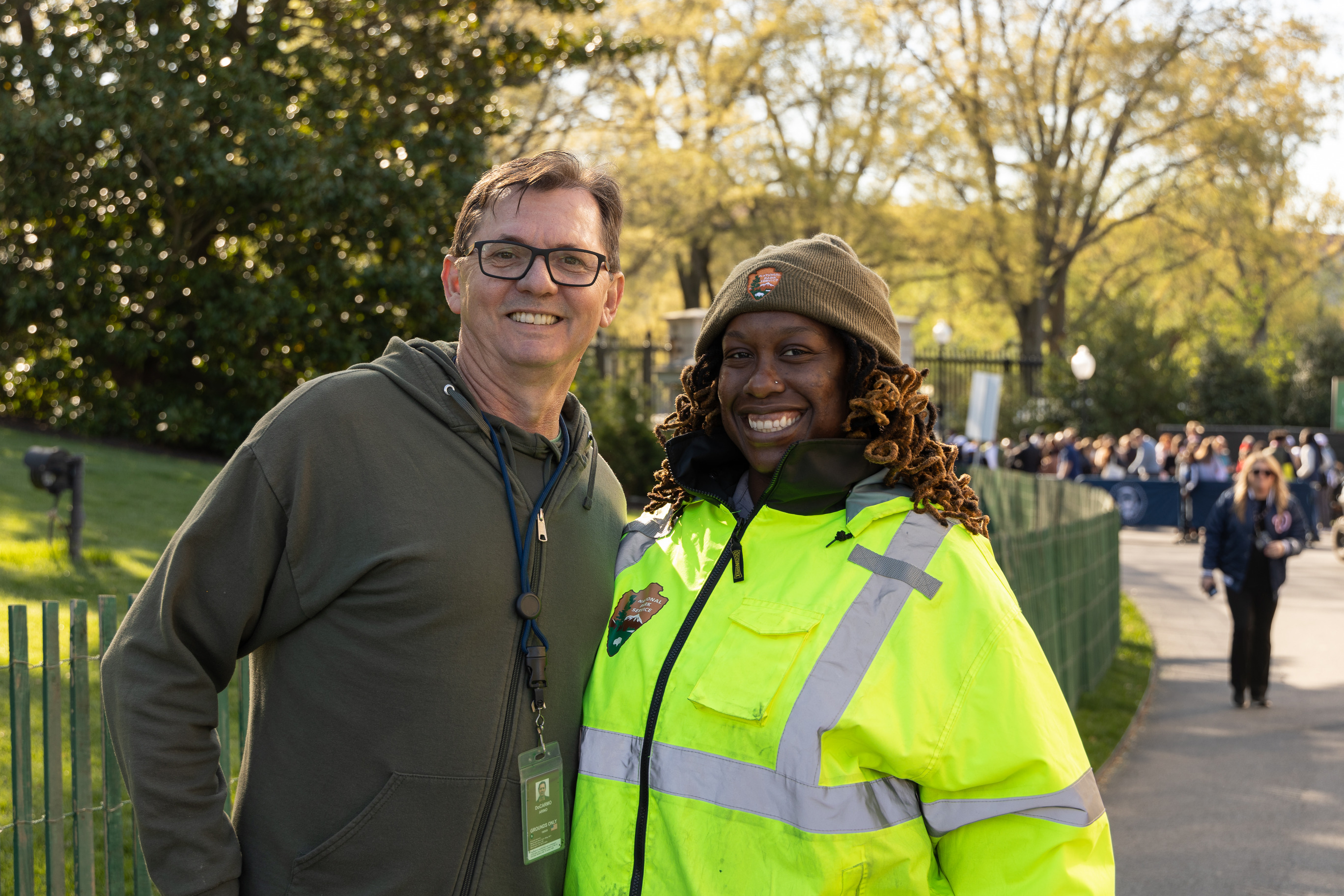 Two national park service park rangers smile next to each other