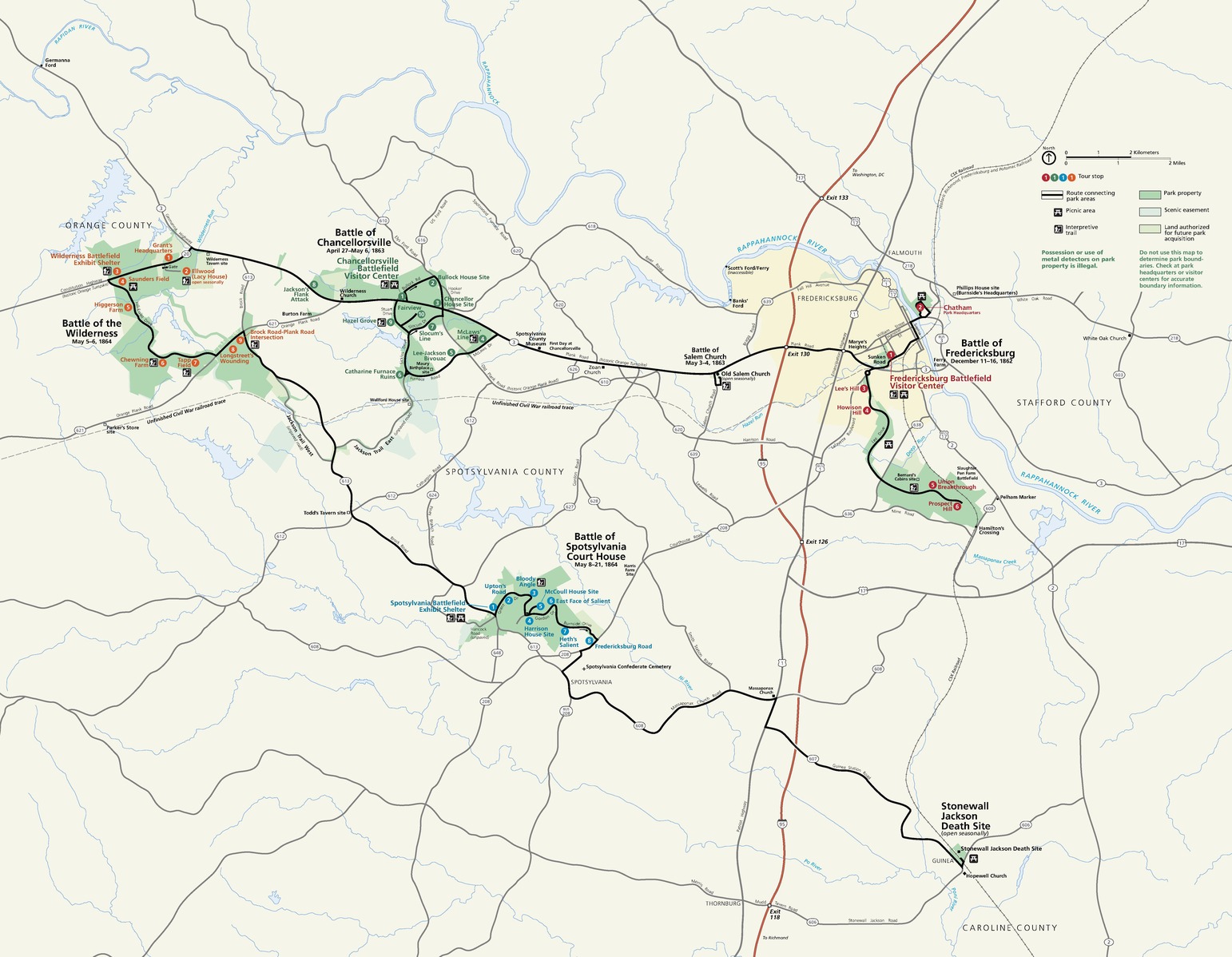 Map of Fredericksburg and Spotsylvania National Military Park in Virginia. The map is tan with parks shown in green. There are four green areas loosely clustered in the center of the map and then a much smaller area near the bottom right corner. Black lines connect the park areas.