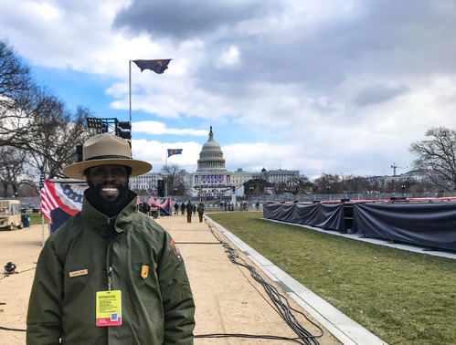 A ranger standing on a wide pathway decorated with flags leading to the U.S. Capitol building
