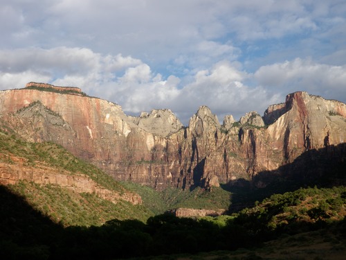 Tall canyon walls are lit by the rising sun. 