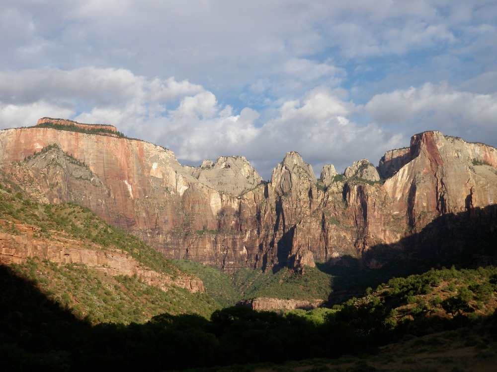 Tall canyon walls are lit by the rising sun. 