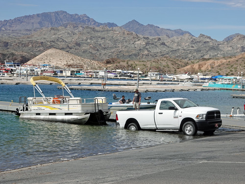 white truck launching pontoon boat at ramp