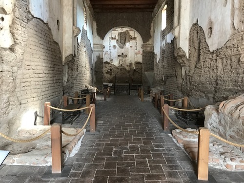 long nave with benches and roped-off side altar remnants, no flowered cross over altar