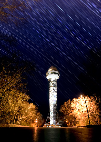 Star lines streak across the night sky while the Mountain Tower remains illuminated in the foreground.