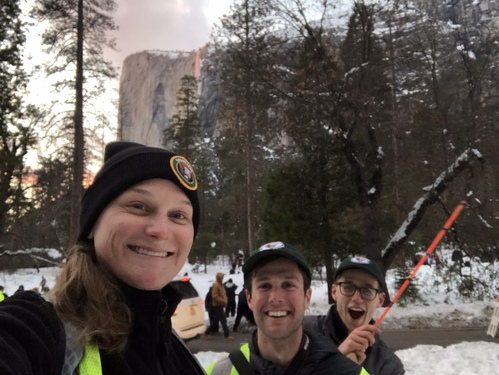 3 people posing in winter landscape with granite cliff and waterfall in the distance