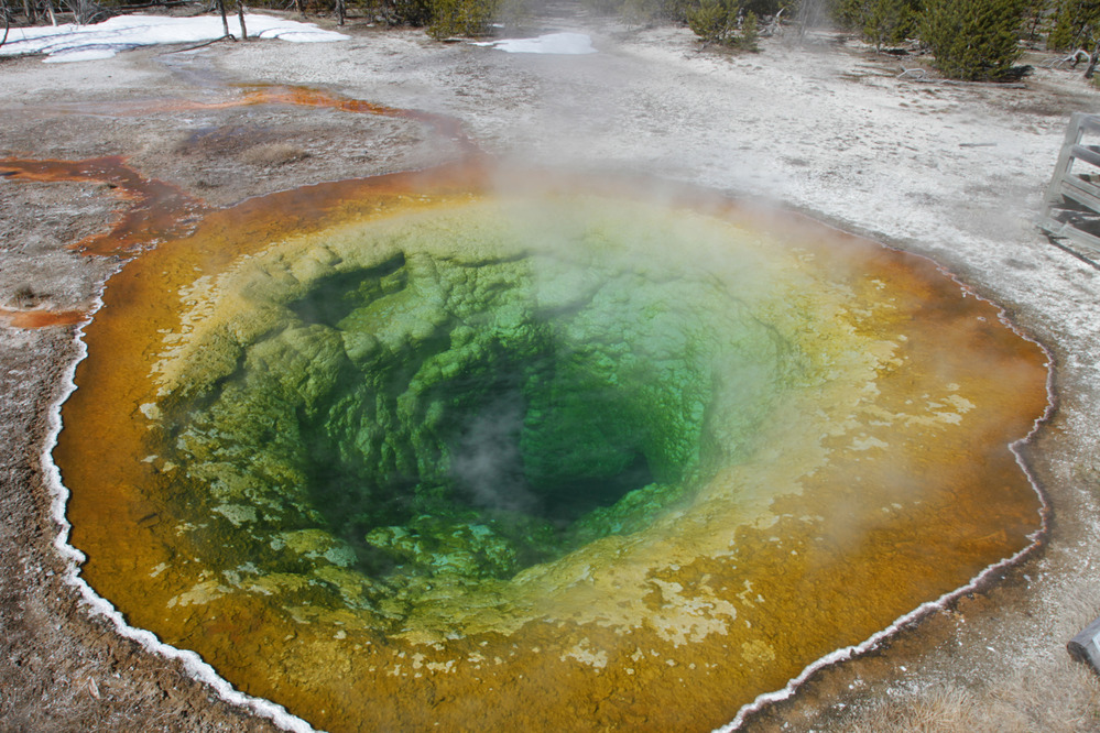 A round pool of hot water is a green color in the center and yellow then orange the farther out you go from the center.
